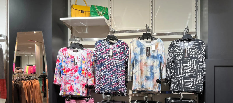 Tops femme à motifs colorés exposés en magasin, sacs à main tendance en arrière-plan