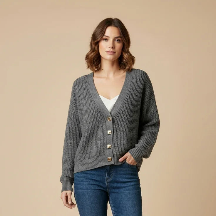 Femme portant un cardigan en maille gris boutonné avec un jean bleu.