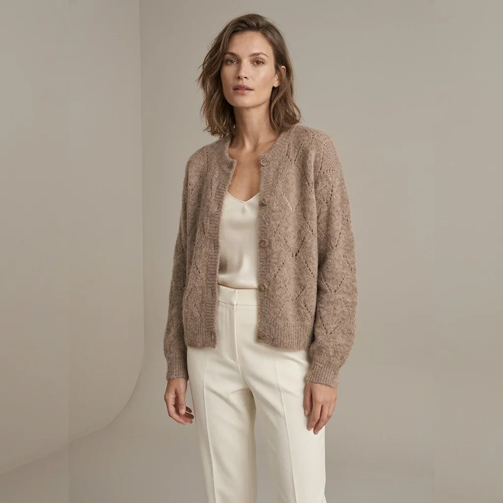Femme portant un cardigan ajouré beige C'est Elle et un pantalon blanc.