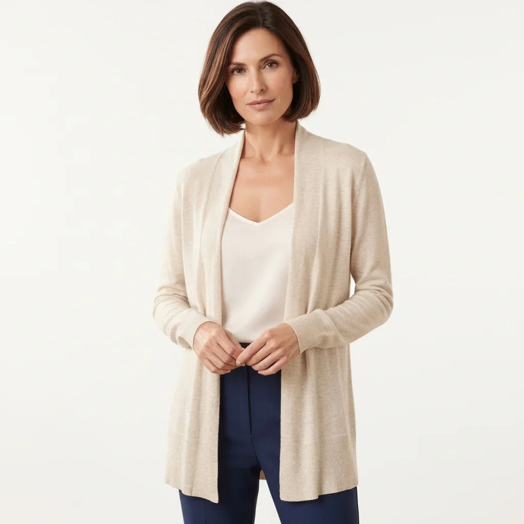 Femme portant un cardigan simple beige ouvert sur un haut blanc et un pantalon bleu marine C'est Elle