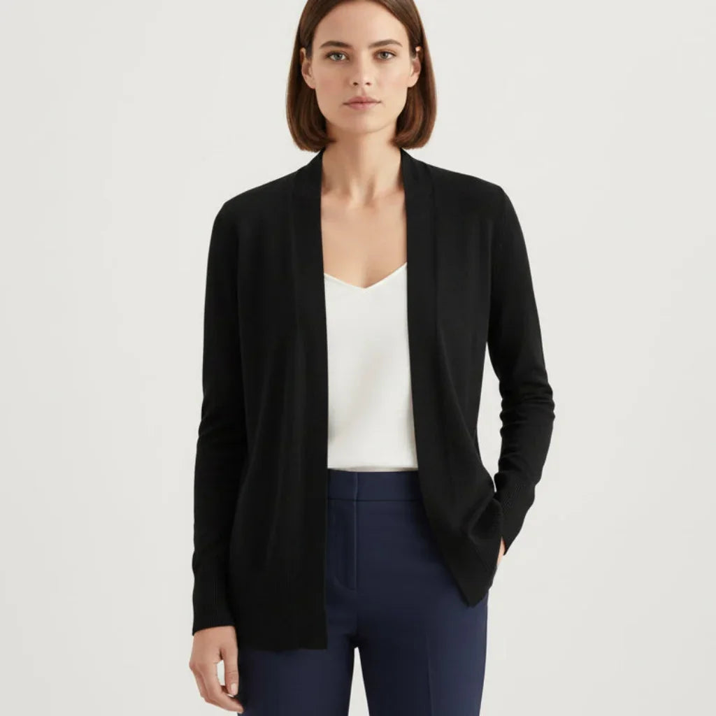 Femme portant un cardigan noir simple C'est Elle sur un haut blanc et un pantalon bleu marine.
