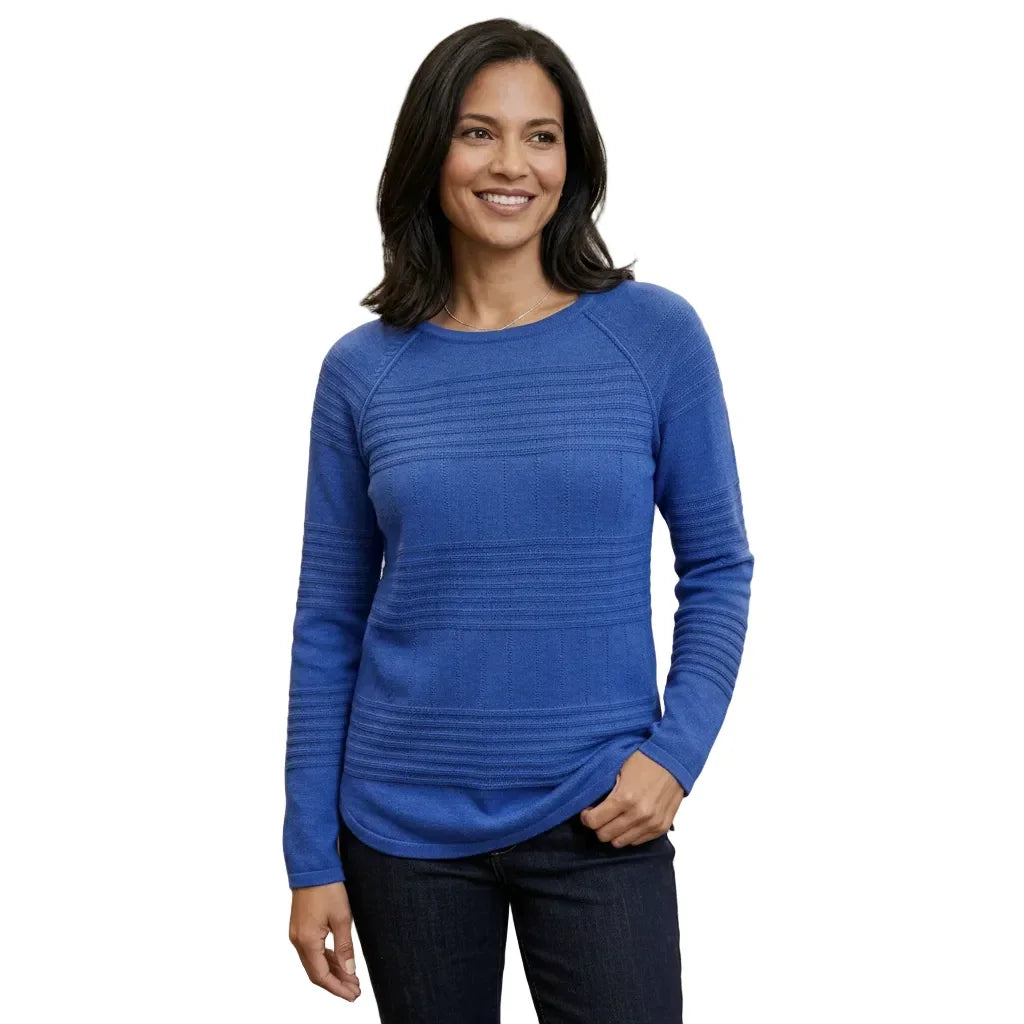 Femme portant un pull bleu à manches longues avec des détails texturés et un jean foncé.