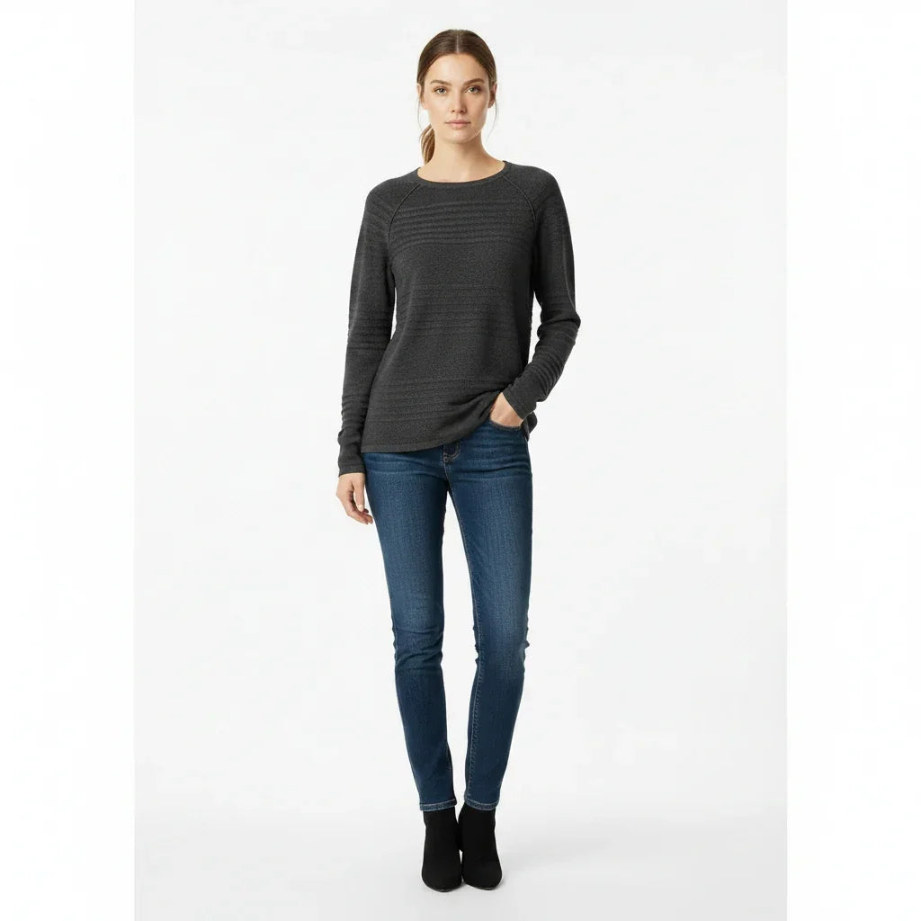 Femme portant un pull gris foncé à manches longues et un jean bleu ajusté.