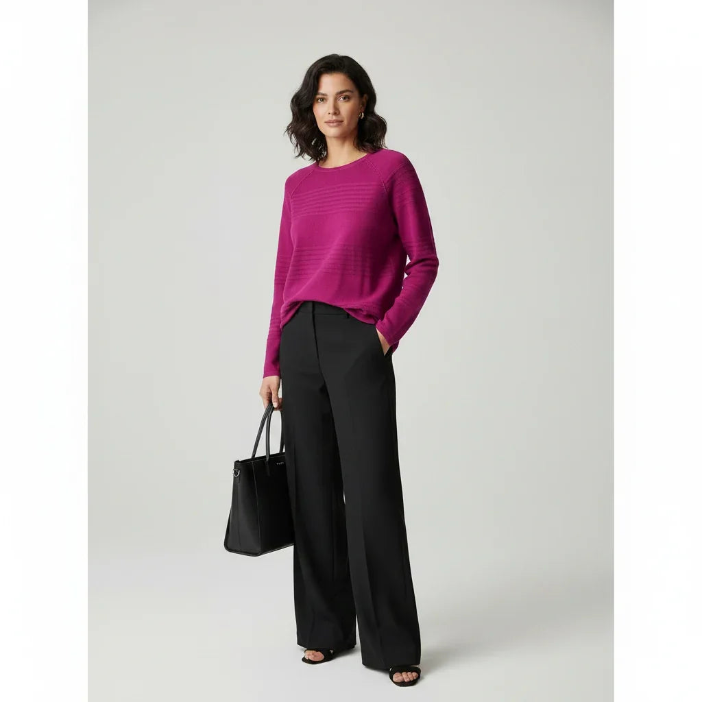 Femme portant un pull rose magenta et un pantalon large noir avec un sac à main noir.