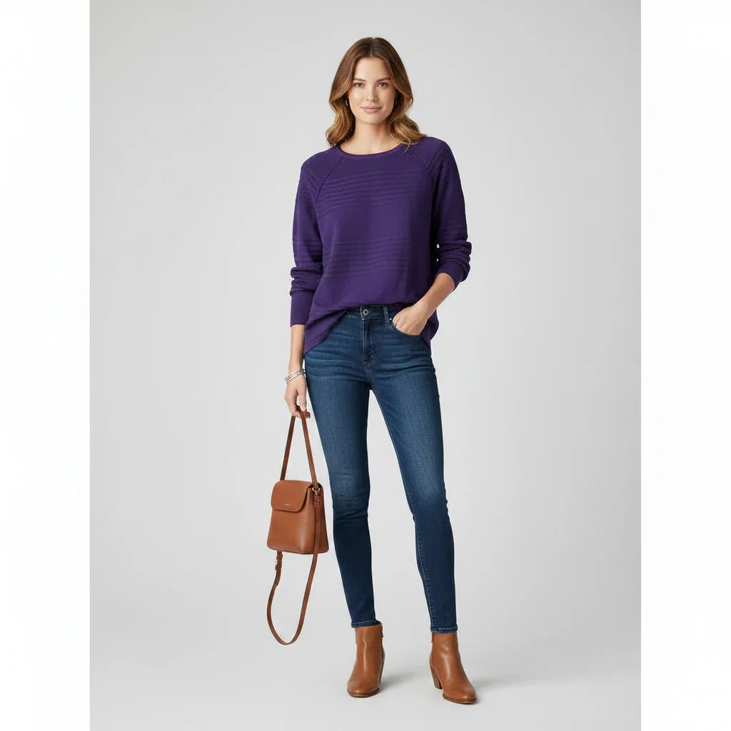 Femme portant un pull violet, un jean bleu et des bottines marron avec un sac à main assorti.