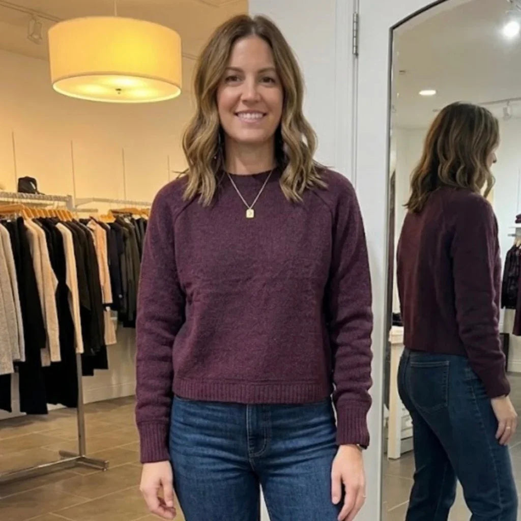 Femme portant un chandail bordeaux Vero Moda et un jean bleu dans une boutique.