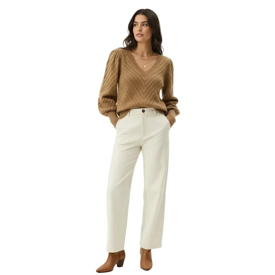 Femme portant un pull beige col V et un pantalon blanc cassé