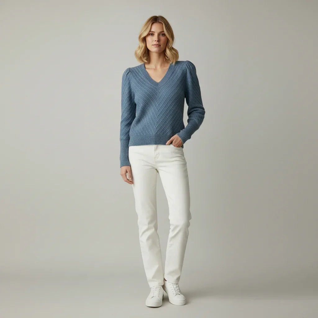 Femme portant un pull bleu à col V et un pantalon blanc
