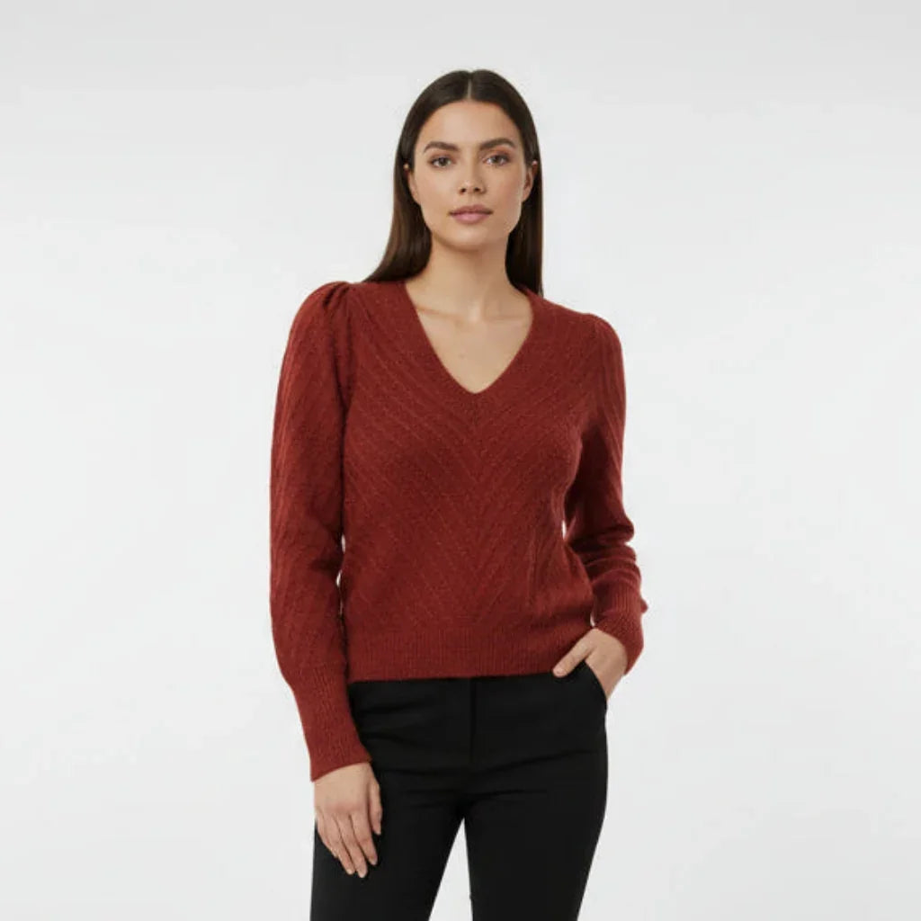Femme portant un pull en maille rouge à col en V et pantalon noir