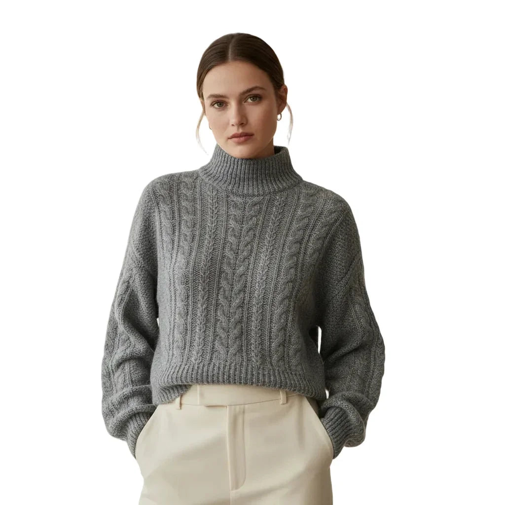 Femme portant un pull gris à col montant avec torsades et un pantalon beige.
