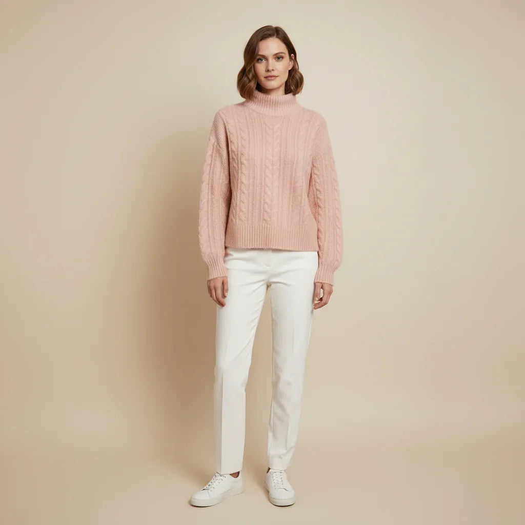 Femme portant un pull en maille torsadée rose pâle et un pantalon blanc