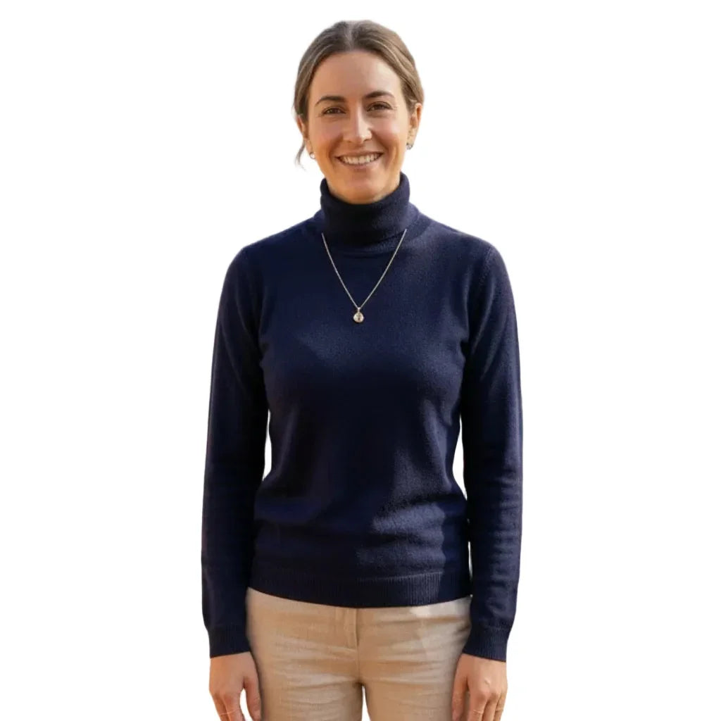 Femme souriante portant un pull à col roulé bleu marine et un pantalon beige.
