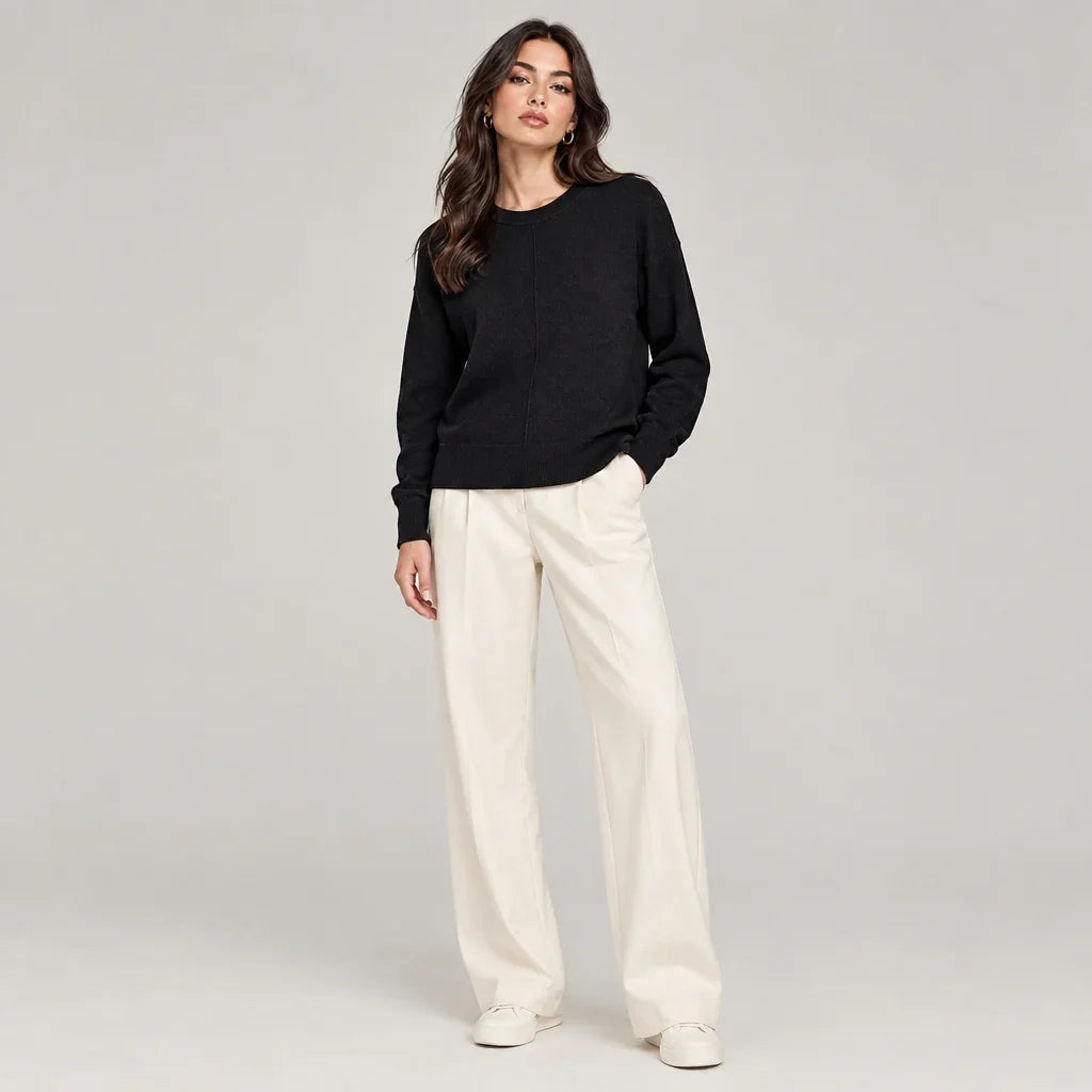 Femme portant un chandail essentials noir et un pantalon blanc large de C'est Elle.