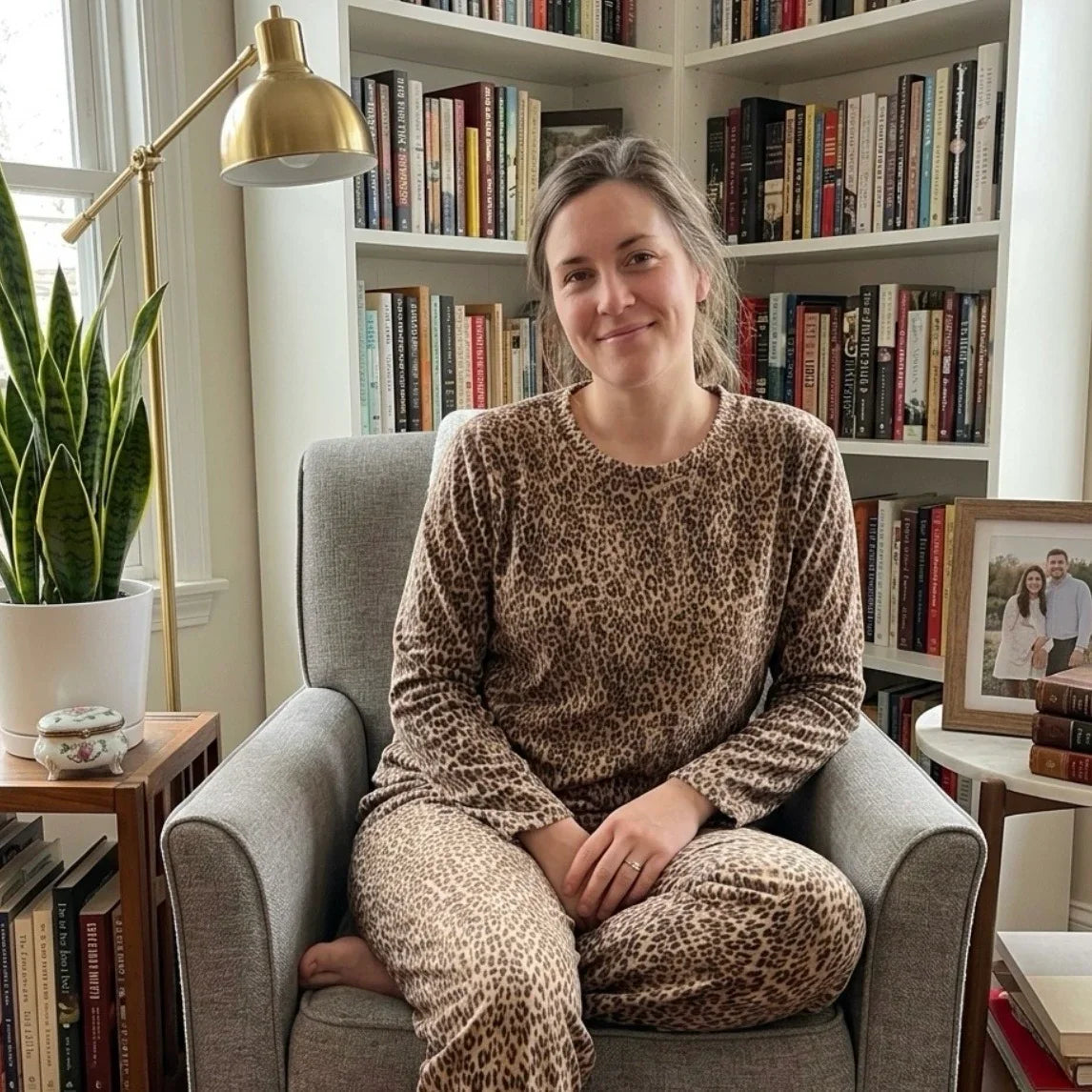 Femme portant un ensemble pyjama imprimé léopard assise dans un fauteuil gris.