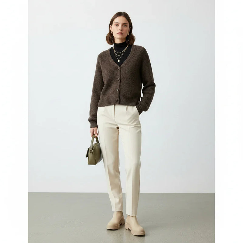 Femme portant un cardigan marron, pantalon blanc cassé et sac à main vert olive.