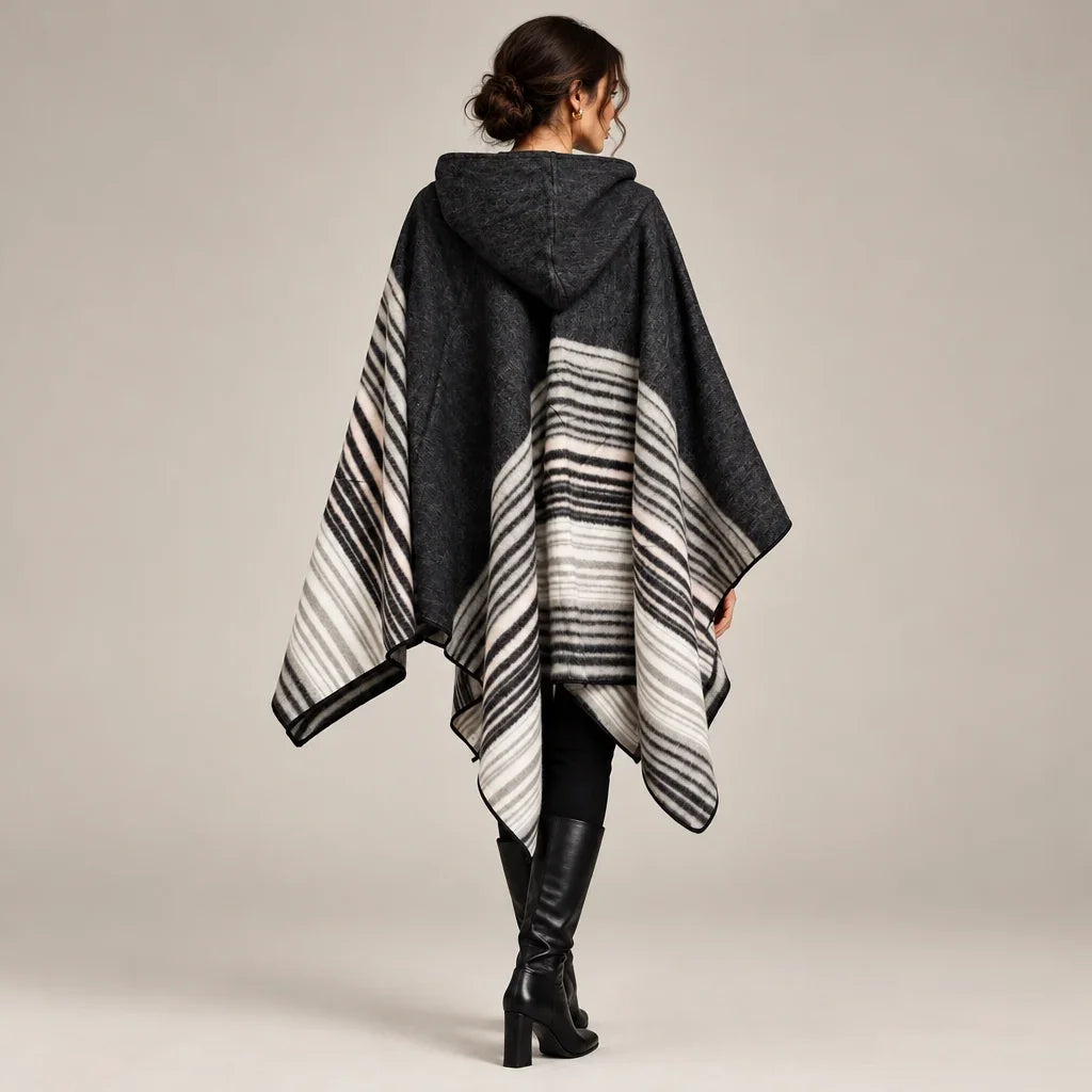 Femme de dos portant un poncho à capuchon gris et blanc rayé de C'est Elle avec bottes noires.