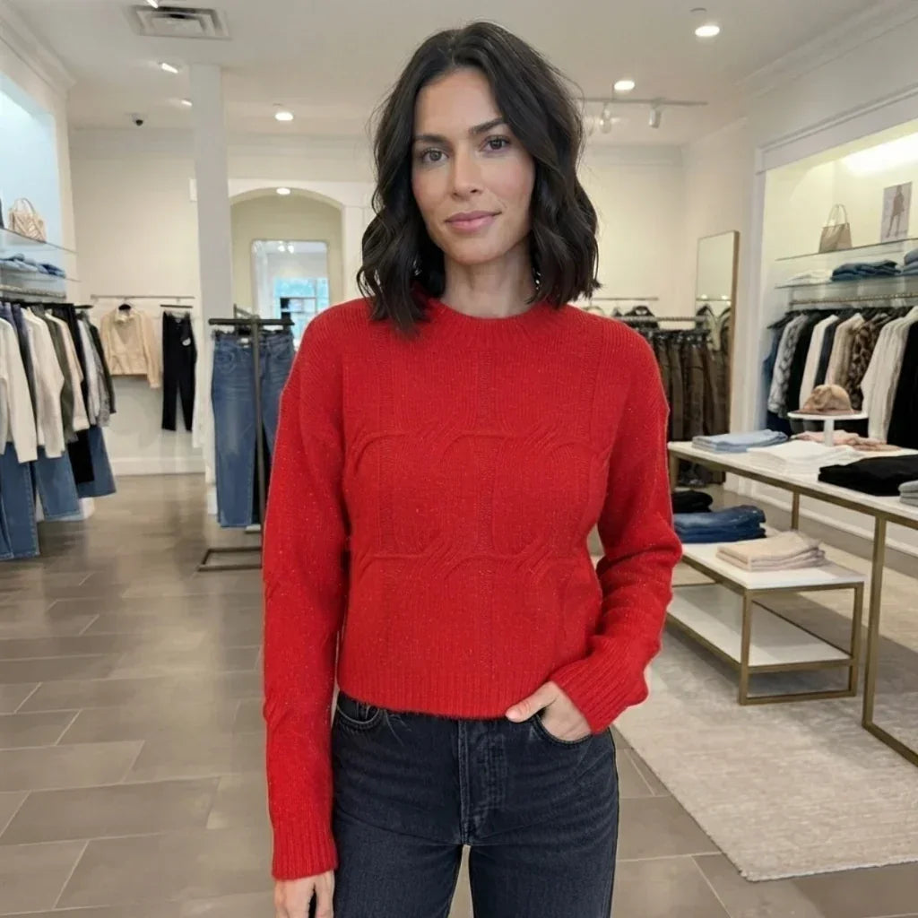 Femme portant un pull col rond texturé rouge C'est Elle et un jean noir en boutique.