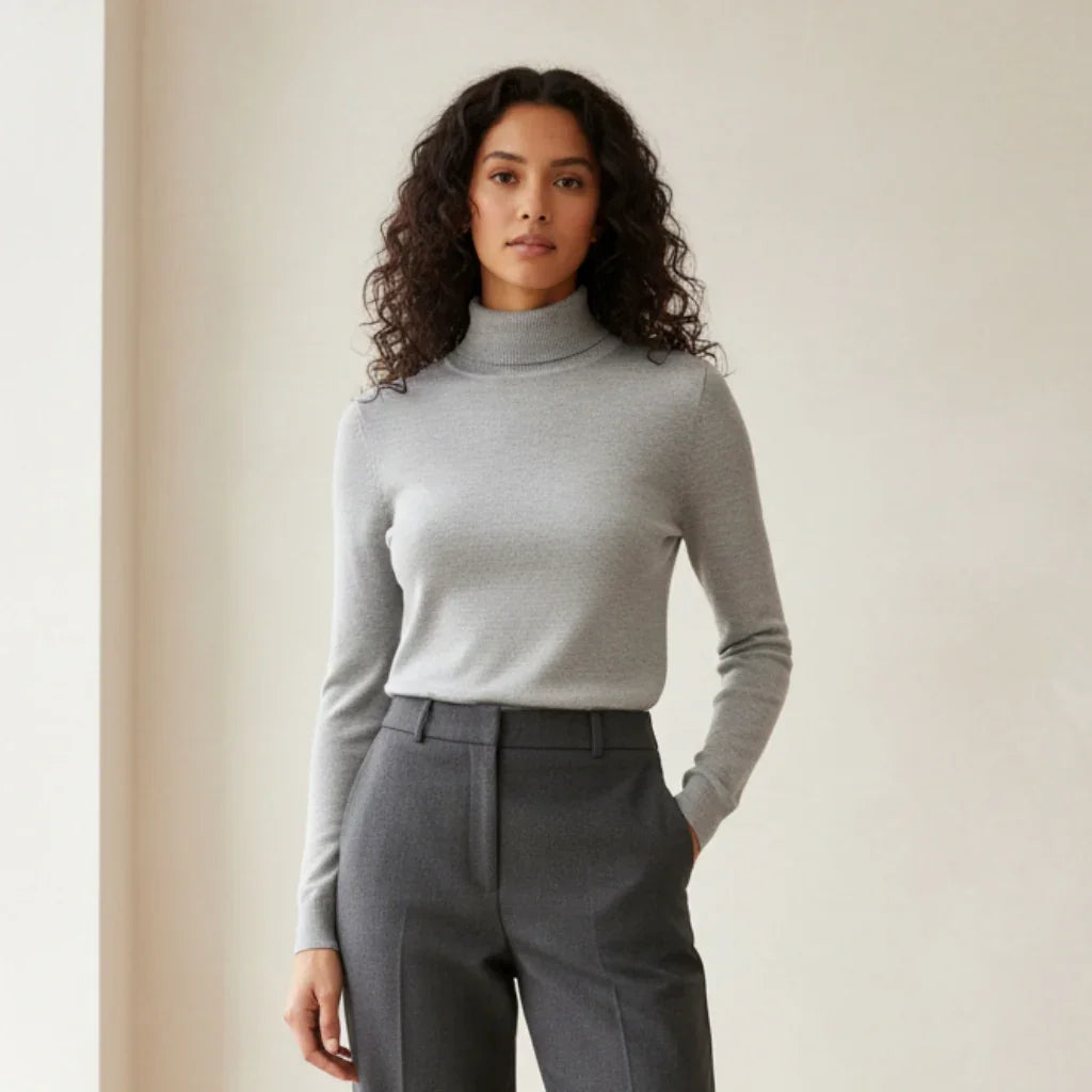 Femme portant un pull à col roulé gris clair et un pantalon tailleur gris foncé.