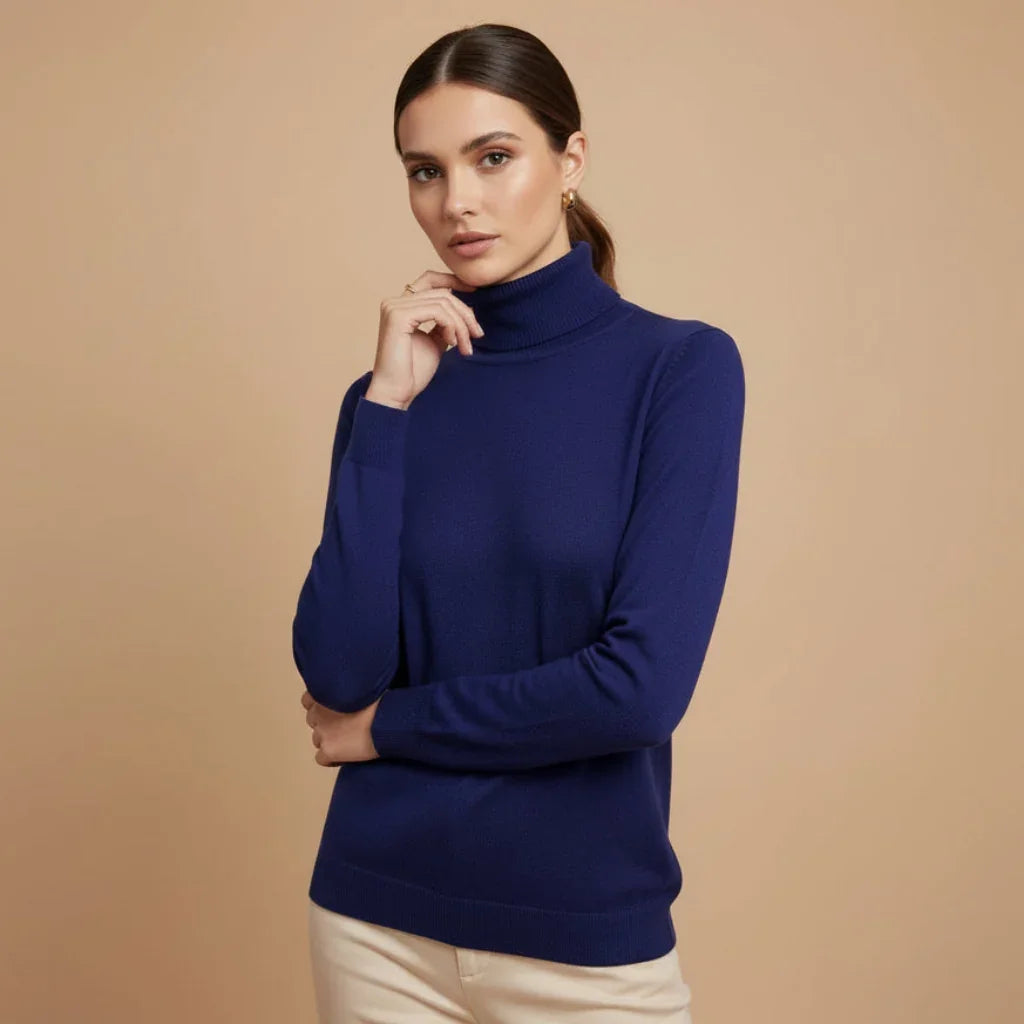 Femme portant un pull à col roulé bleu marine ajusté sur fond beige.