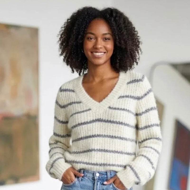 Femme portant un pull en maille blanc à rayures grises et col en V