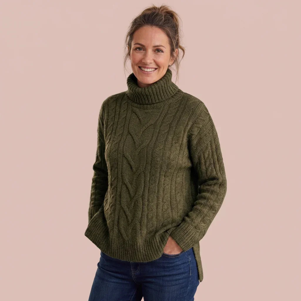 Femme portant un pull col roulé en maille torsadée vert olive et un jean bleu.