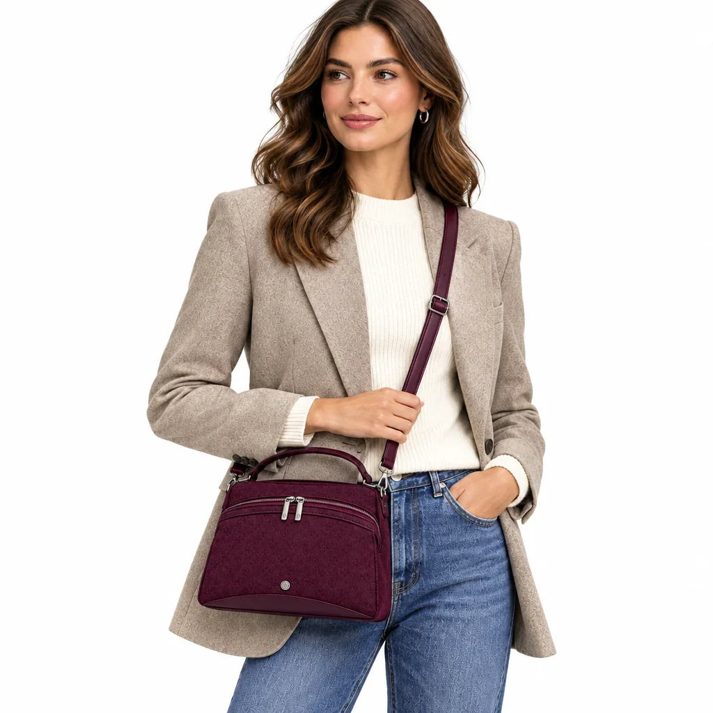 Femme portant un sac à main en daim bordeaux C'est Elle avec un blazer beige et un jean bleu.