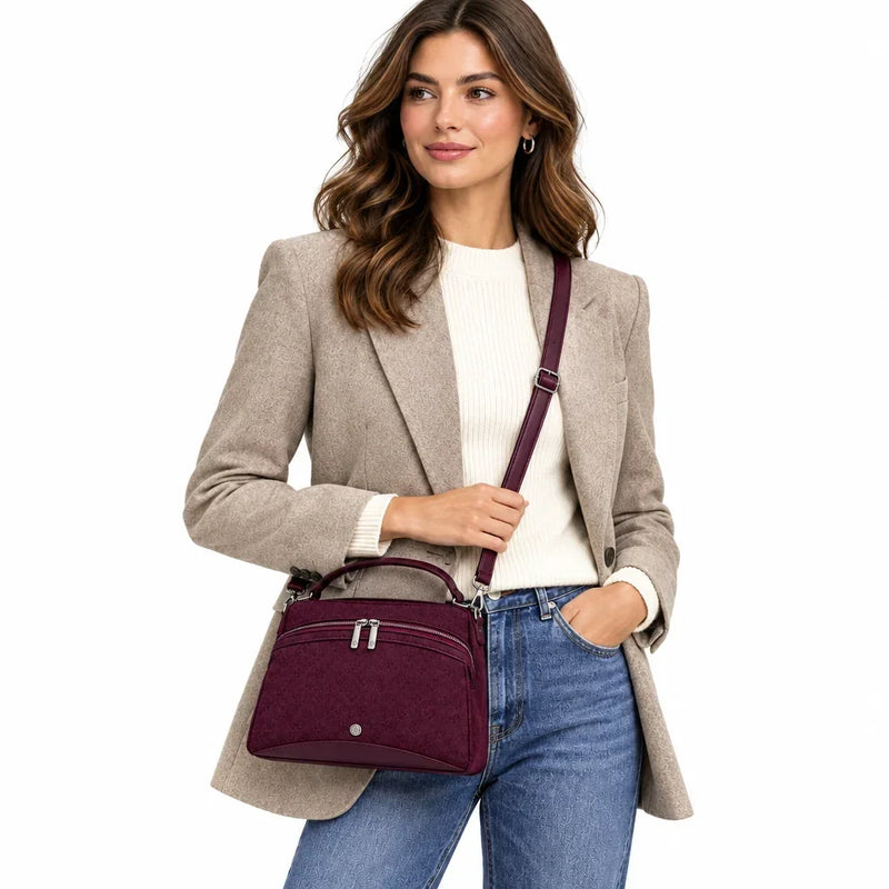 Femme portant un sac à main en daim bordeaux C'est Elle avec un blazer beige et un jean bleu.