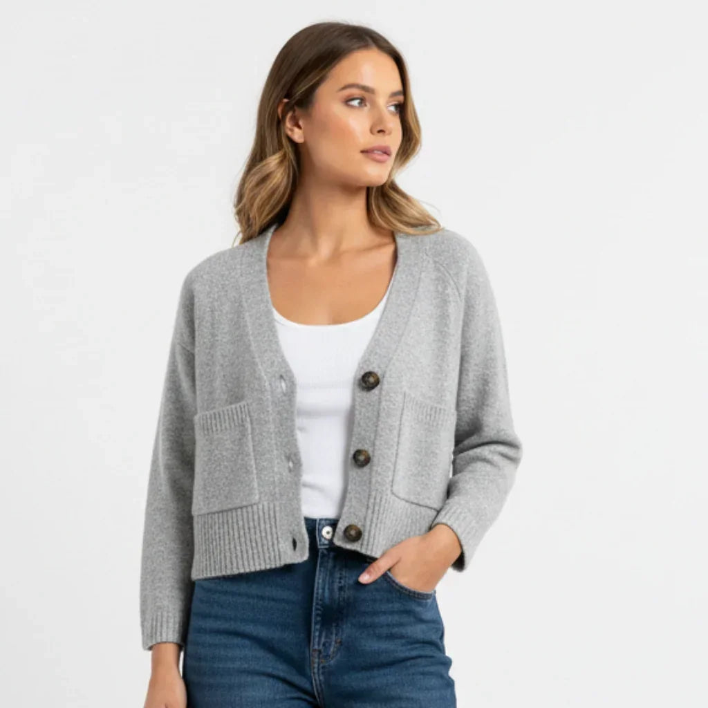 Femme portant un cardigan gris C'est Elle avec poches sur un t-shirt blanc et jean bleu.