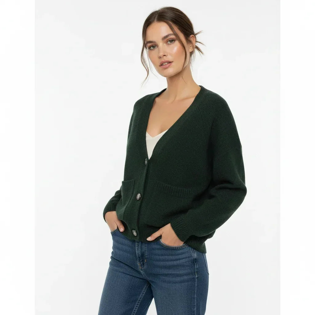 Femme portant un cardigan vert foncé à poches et un jean bleu de C'est Elle