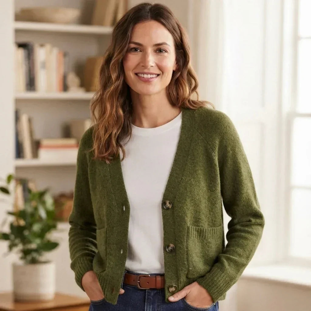 Femme portant un cardigan vert olive C'est Elle sur un t-shirt blanc et un jean bleu.