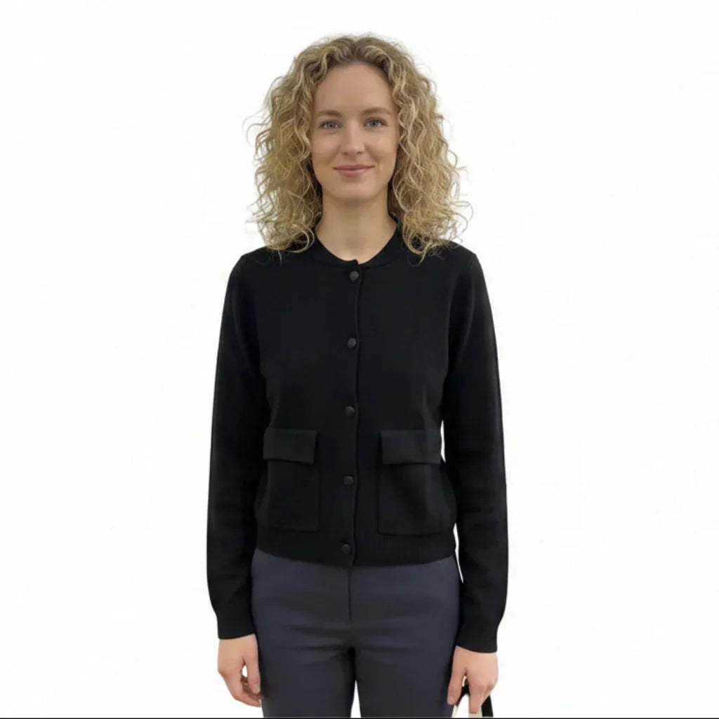 Femme portant un cardigan noir boutonné avec poches et un pantalon gris.
